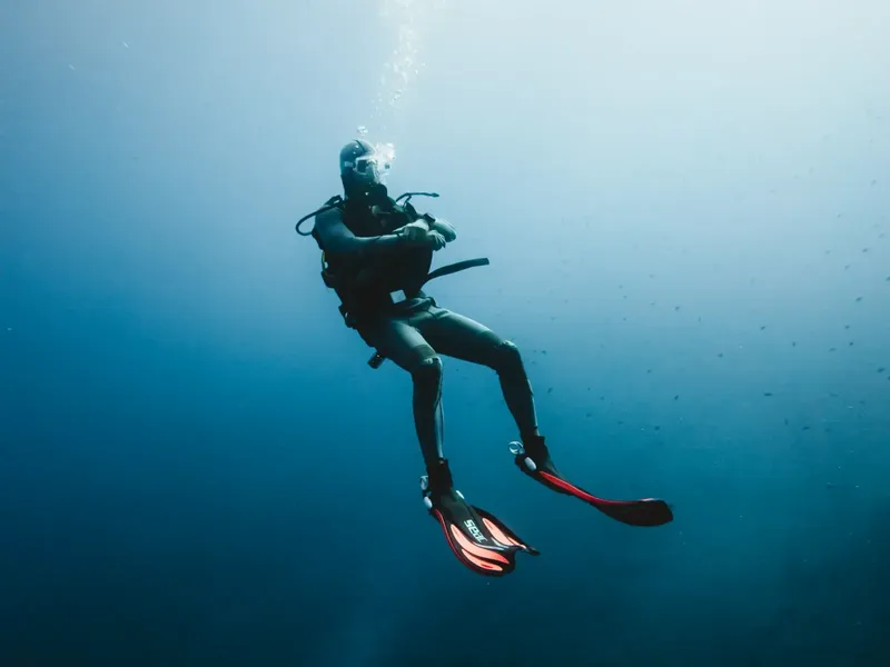 Plongeur en combinaison nageant dans une eau bleue et claire