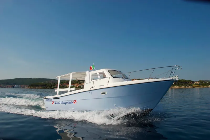 Bateau de plongée bleu naviguant sur une mer calme et ensoleillée