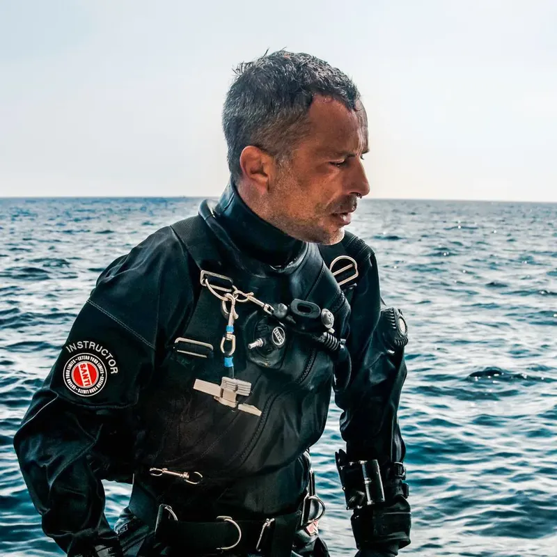 Plongeur en combinaison noire regarde au loin sur une mer calme