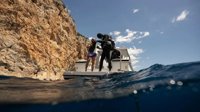 Plongeur s'équipant sur un bateau avec une falaise en arrière-plan
