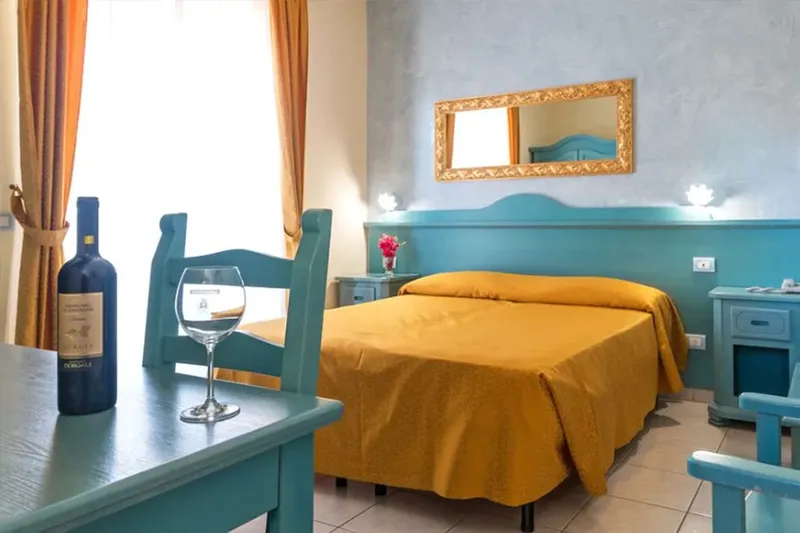 Chambre d'hôtel avec lit jaune, bouteille de vin et décoration