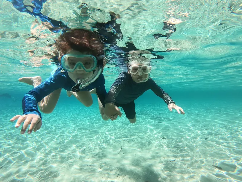 Deux personnes nagent avec masque et tuba dans une eau turquoise claire