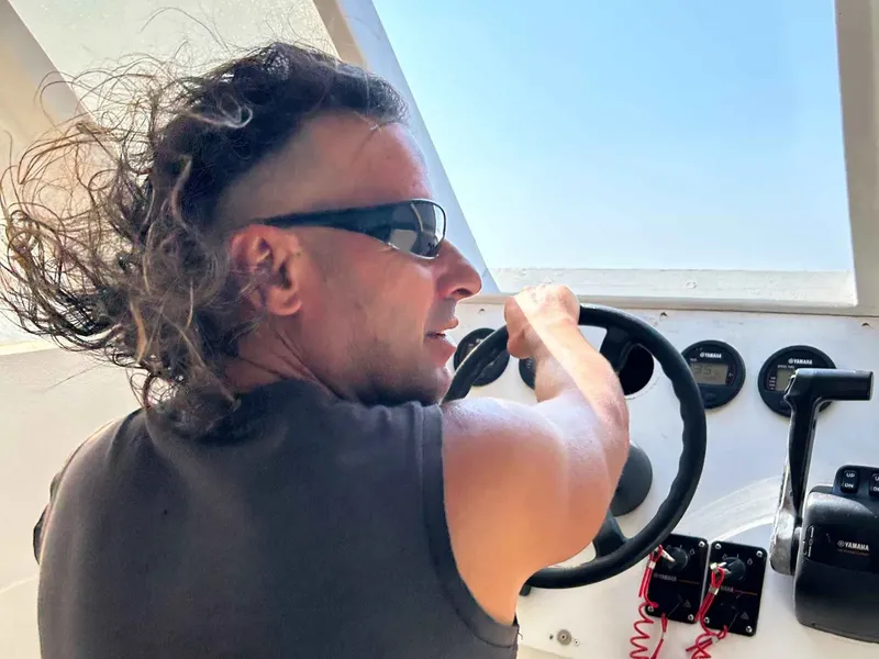 Homme conduisant un bateau de plaisance avec des lunettes de soleil