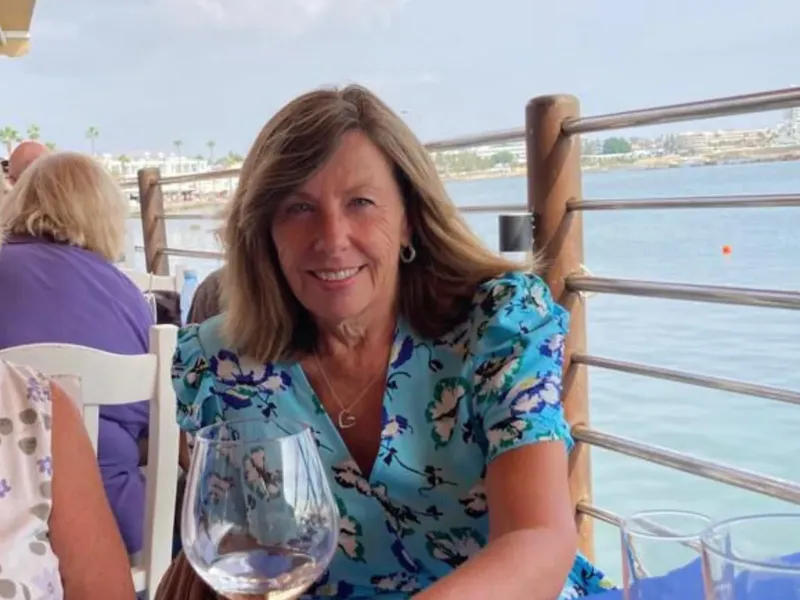 Femme souriante assise en terrasse avec vue sur la mer
