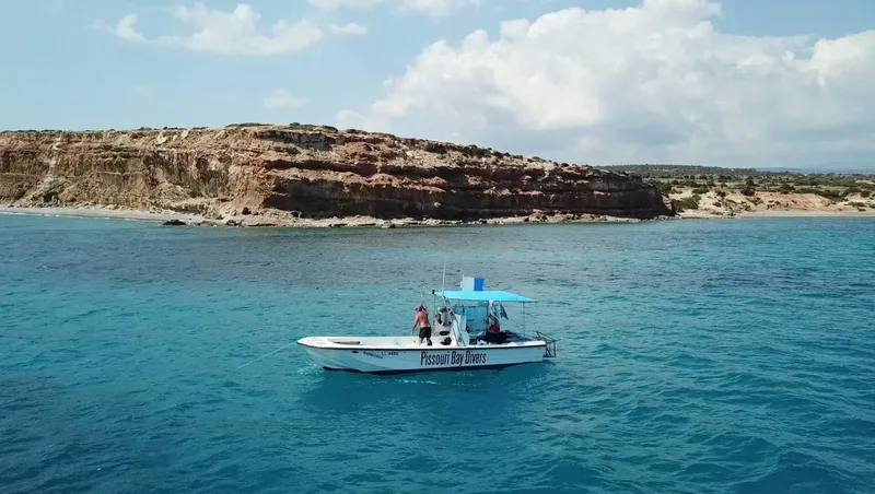 Bateau de plongée navigue en mer face à une côte rocheuse