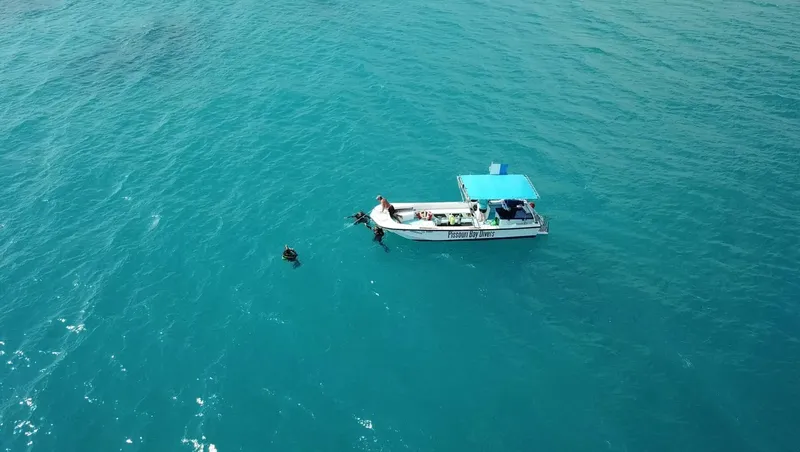Bateau de plongée avec des personnes entrant dans l'eau turquoise