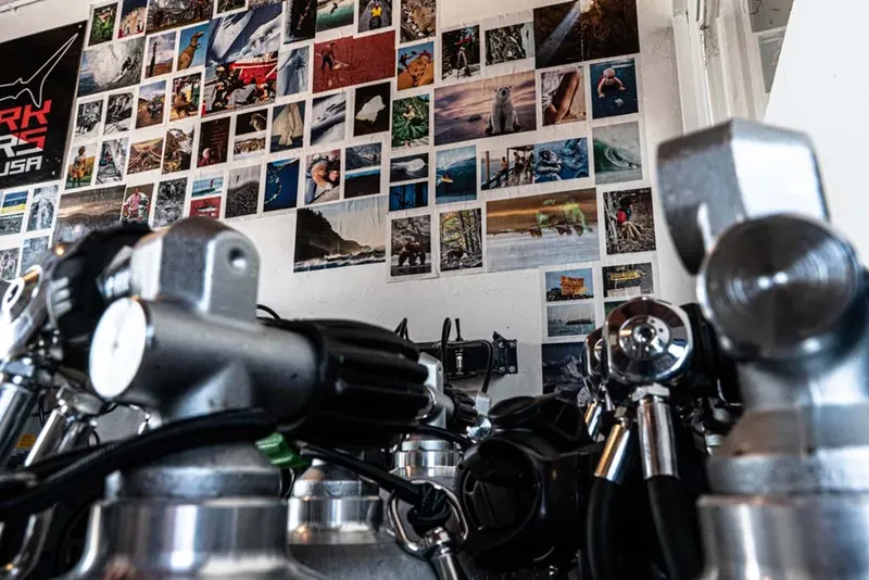 Rangement de bouteilles de plongée devant un mur de photos sous-marines