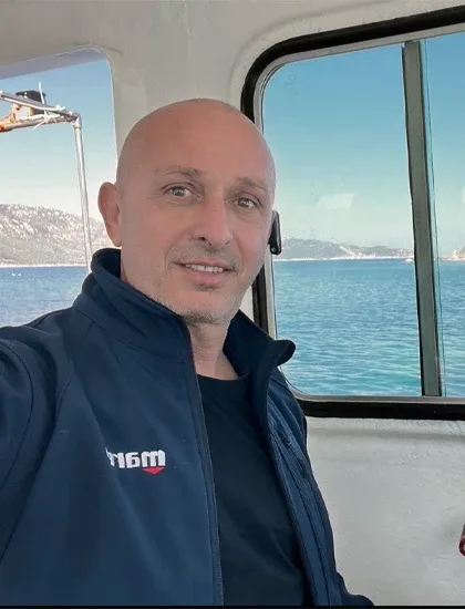 Homme souriant sur un bateau avec la mer en arrière-plan