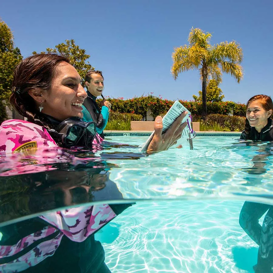 Plongeuses en formation, une lit des instructions au bord d'une piscine