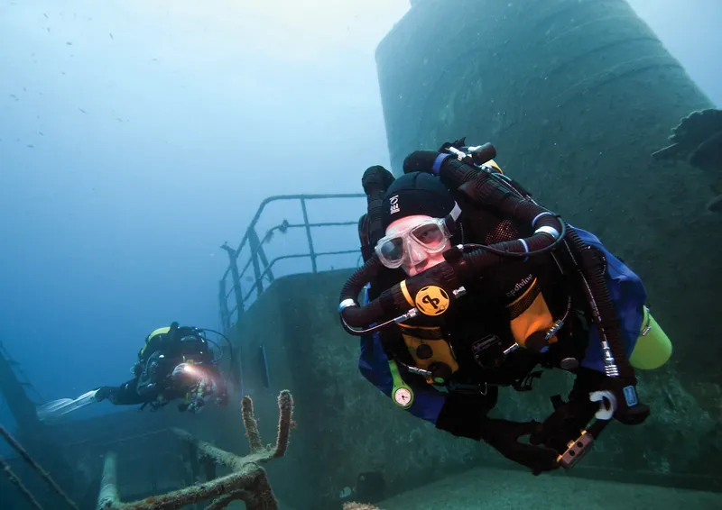 Deux plongeurs explorent l'épave d'un grand navire sous-marin