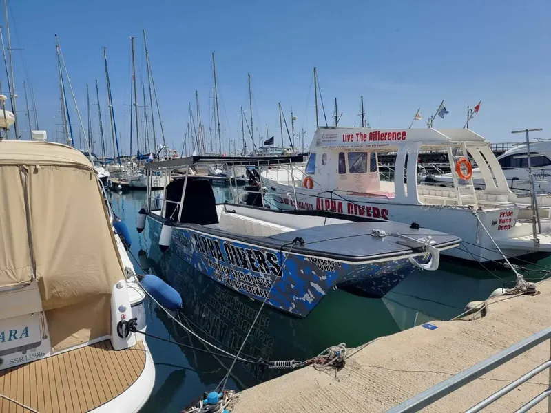 Bateau de plongée amarré dans un port ensoleillé avec du texte