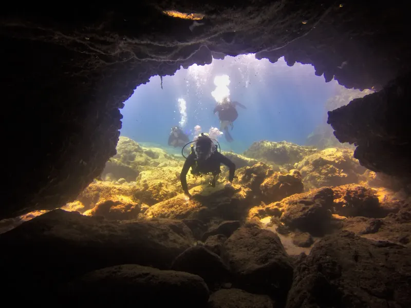 Plongeurs explorent une grotte sous-marine avec des rayons de lumière