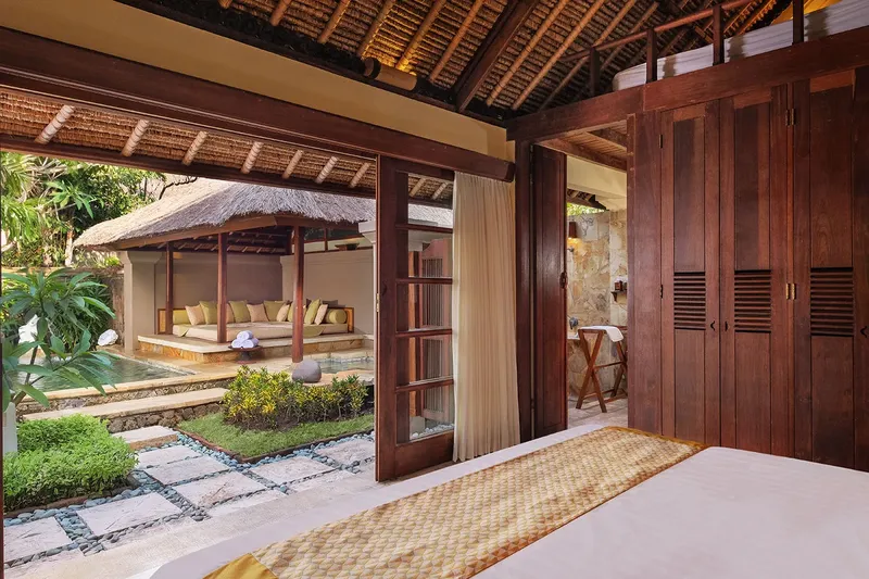 Intérieur d'une chambre ouverte sur une piscine et un jardin tropical