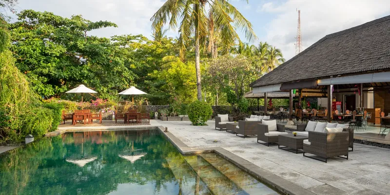 Piscine et terrasse ombragée avec mobilier de jardin et végétation tropicale