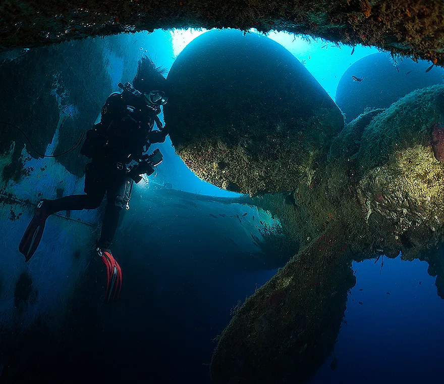 Plongeur explorant l'épave d'un navire, lumière bleue, ambiance mystérieuse