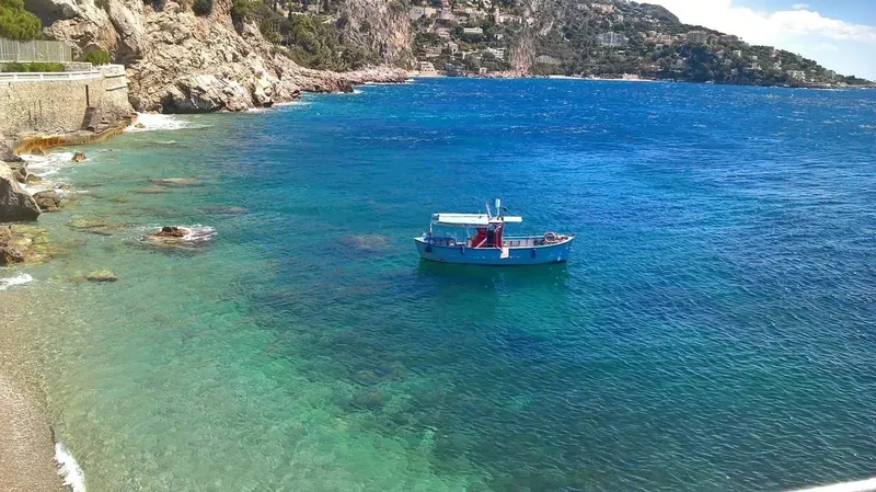 Vue aérienne d'un bateau bleu amarré dans une crique rocheuse