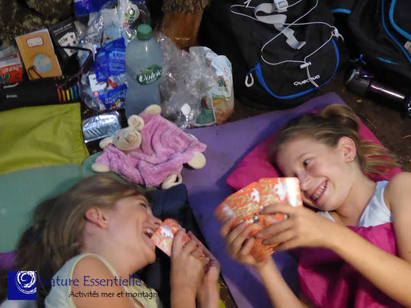 Deux jeunes filles souriantes mangent des frites, allongées sur un matelas