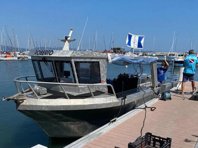 Bateau de plongée amarré à un ponton avec des équipements et des personnes