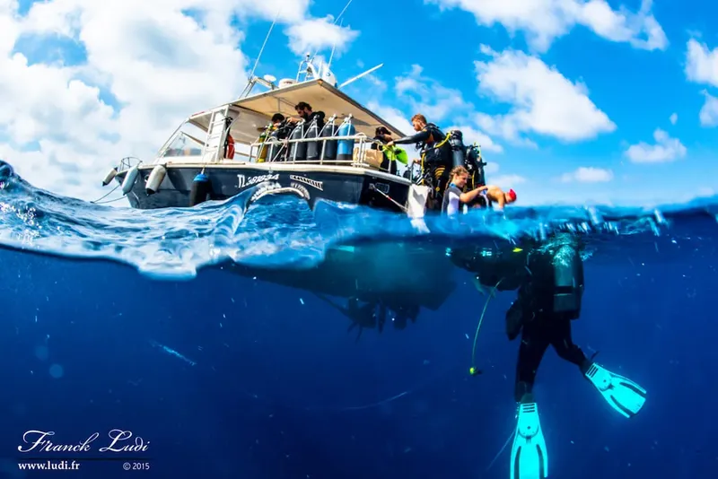 Plongeurs s'équipent sur un bateau, vue moitié hors d'eau moitié sous-marine