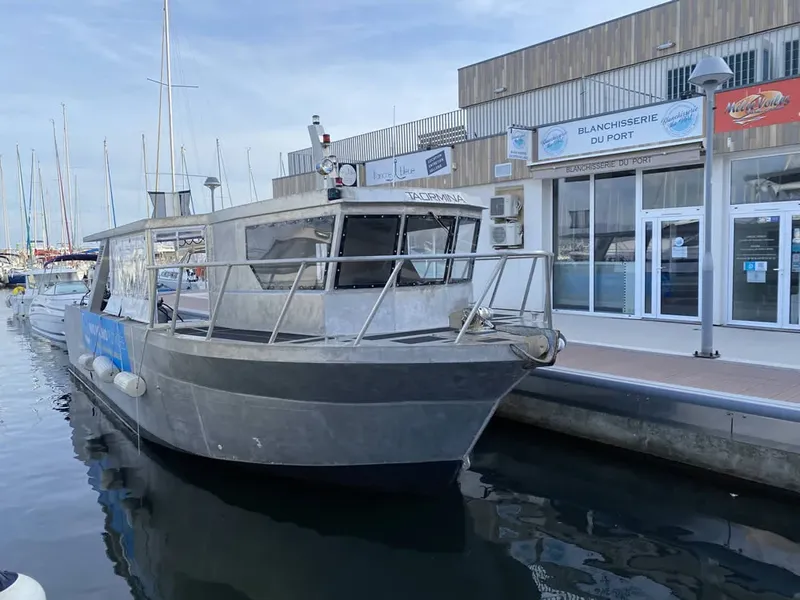 Bateau de plongée amarré à un quai devant des bâtiments portuaires