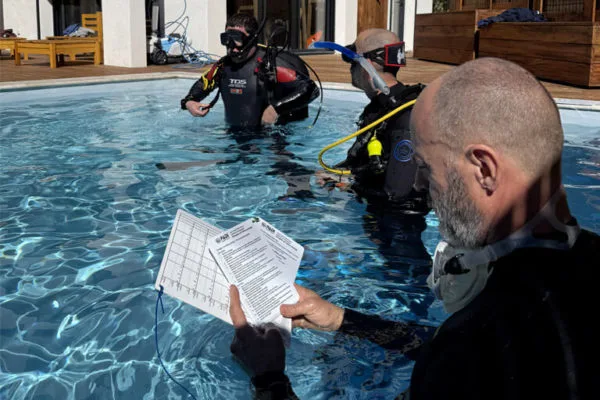 Plongeurs en formation dans une piscine, un instructeur présente un document