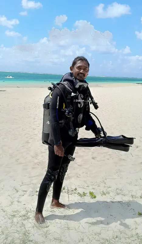 Plongeur souriant sur une plage de sable blanc avec son équipement