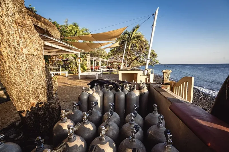 Bouteilles de plongée devant une structure abritée avec vue sur la mer