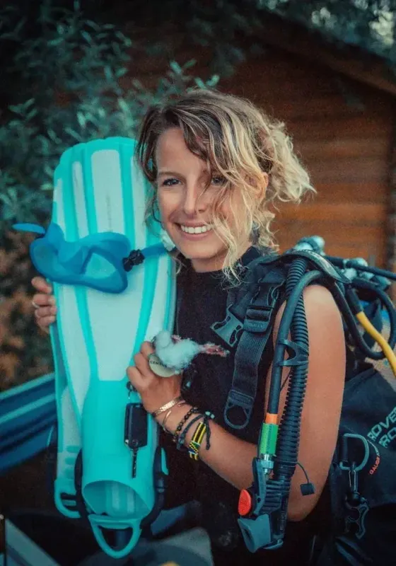 Plongeuse souriante tenant masque et palmes, equipement complet visible