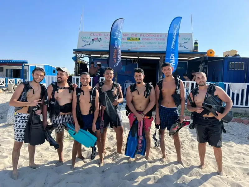 Groupe de plongeurs équipés devant le centre de plongée sur plage