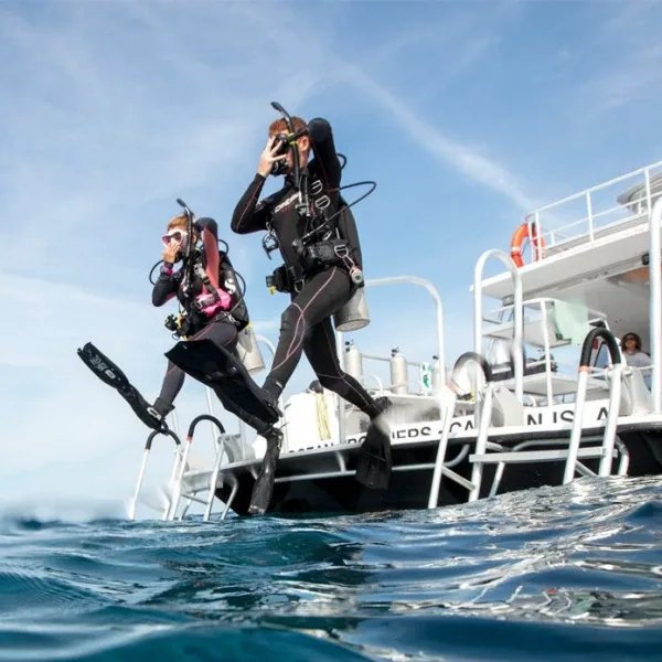 Deux plongeurs sautent d'un bateau de plongée en pleine mer