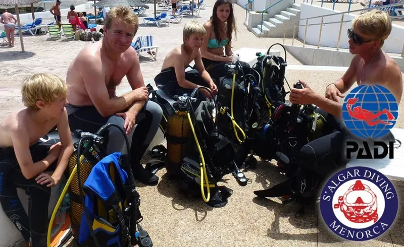 Groupe de plongeurs équipés sur une plage ensoleillée avec logos PADI