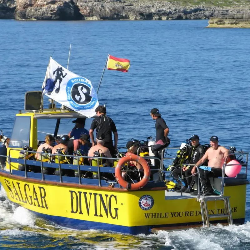 Bateau de plongée jaune avec des plongeurs et des drapeaux en mer