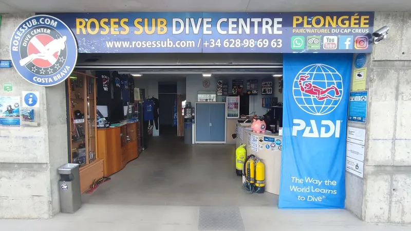 Devanture d'un centre de plongée avec enseigne, matériel et logos PADI
