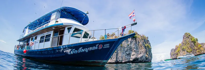 Bateau de plongée bleu et blanc amarré près d'une formation rocheuse