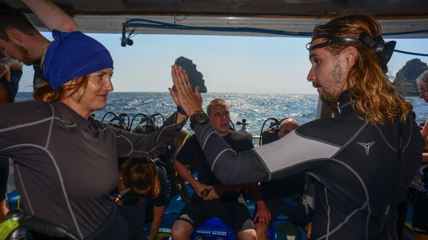 Plongeurs sur un bateau se félicitent avec un high-five en mer