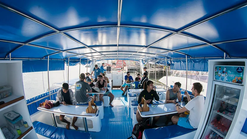 Groupe de personnes assises sur un bateau de plongée bleu