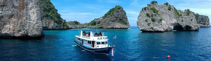 Bateau de plongée navigue entre les îles rocheuses sous un ciel bleu