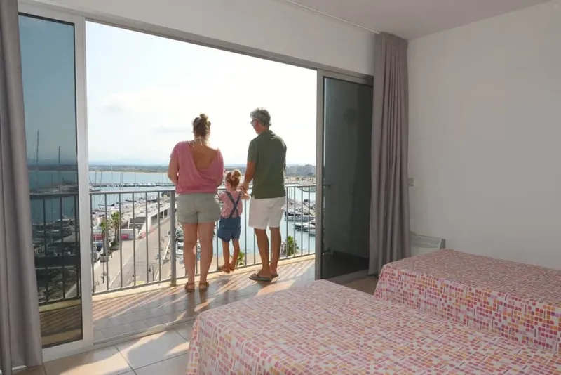Famille admirant la vue sur le port depuis une chambre d'hôtel