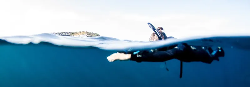 Apnea : plongeur en surface, moitié corps immergé, vue panoramique