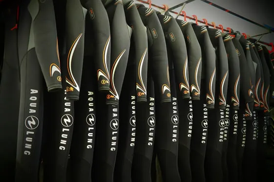 Rangée de combinaisons de plongée noires Aqualung suspendues à des cintres