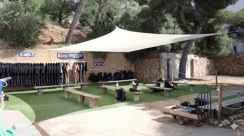 Equipement de plongée rangé sur des bancs devant un mur et un abri