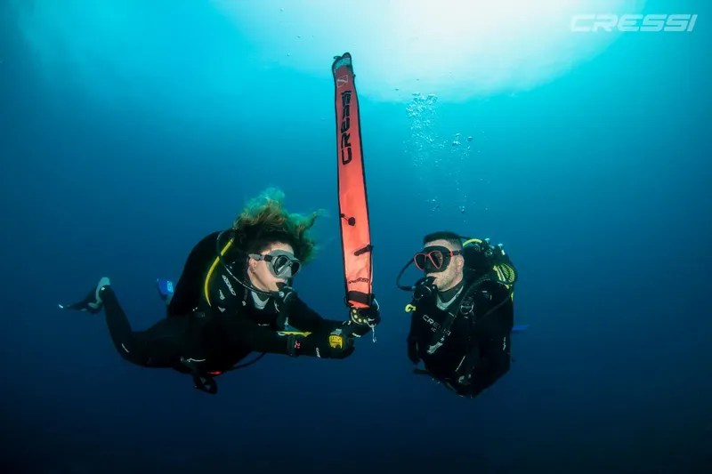 Deux plongeurs en combinaison explorent les profondeurs sous-marines avec un balisage