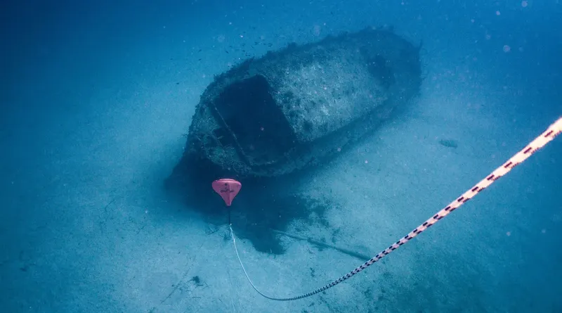 Epave de bateau reposant sur le fond marin, balisée par un filin