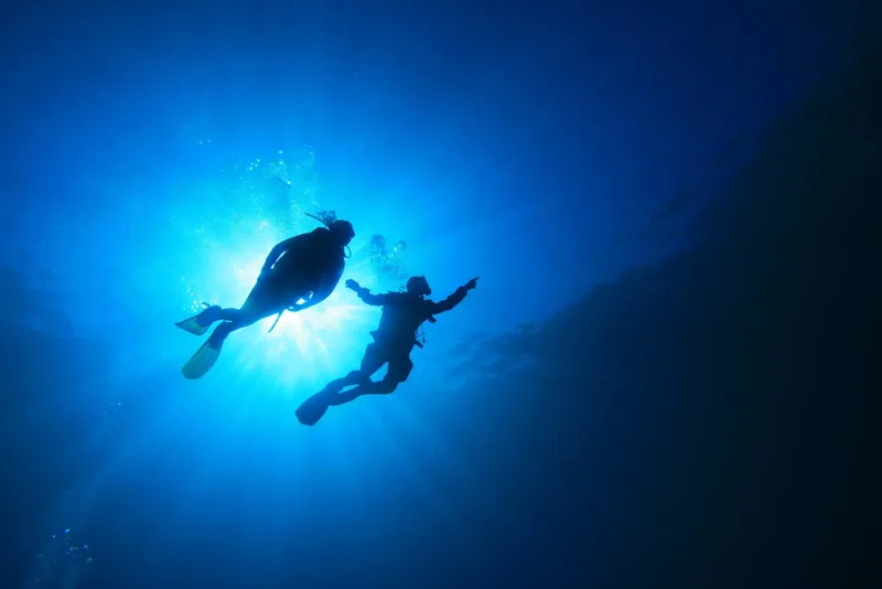 Deux plongeurs évoluent en apnée dans une eau bleue lumineuse
