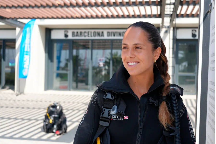 Plongeuse souriante avec équipement devant le centre de plongée