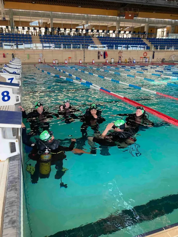 Groupe de plongeurs en formation dans une piscine couverte éclairée