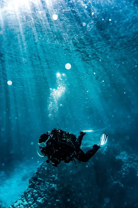 Plongeur en combinaison noire explore un monde aquatique bleu et lumineux