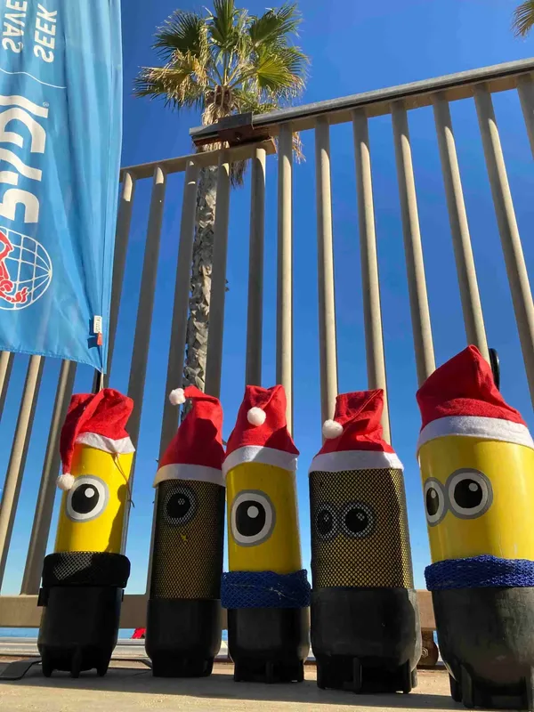 Bouteilles de plongée décorées de bonnets de Père Noël devant un ponton