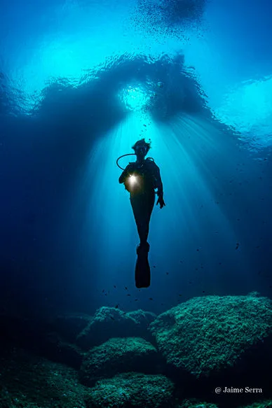 Plongeur silhouette sombre, rayons de lumière, fond marin rocheux