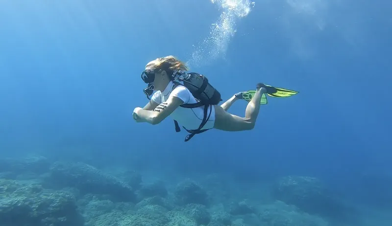 Plongeuse en combinaison explore les fonds marins bleus et clairs